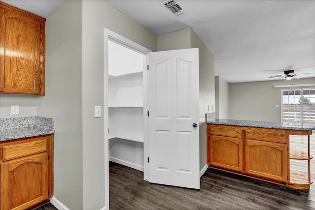 kitchen with a textured ceiling, ceiling fan, kitchen peninsula, and dark wood-type flooring