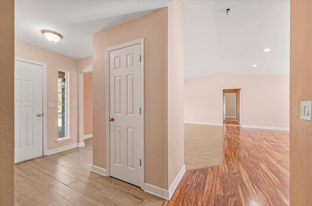 hall with lofted ceiling and light wood-type flooring