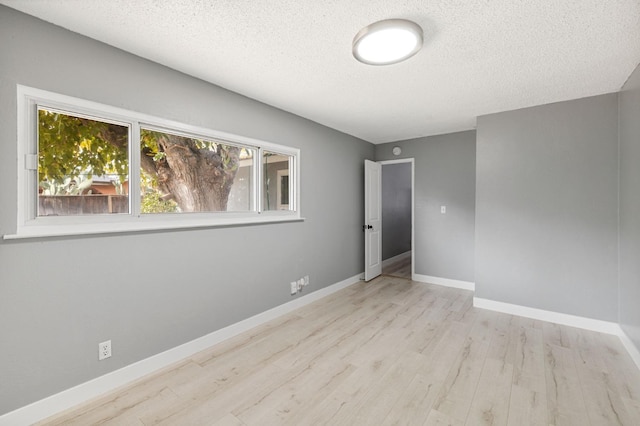 empty room featuring light hardwood / wood-style flooring and a textured ceiling