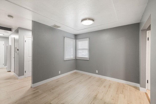 empty room with a textured ceiling and light wood-type flooring