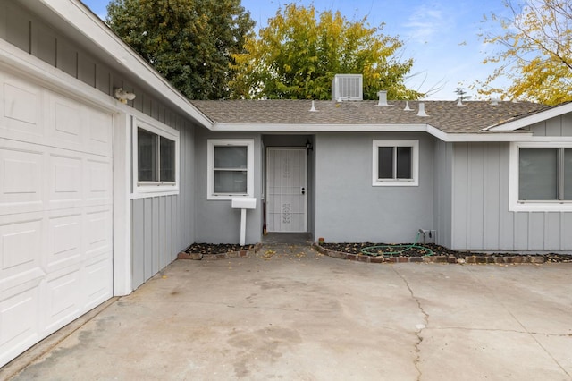 property entrance featuring a garage, a patio, and central air condition unit