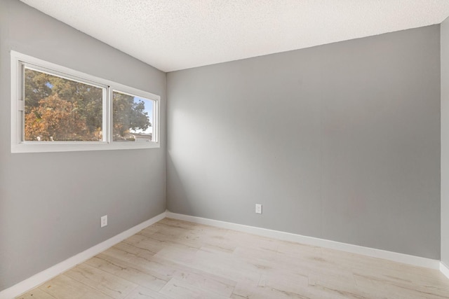 unfurnished room with a textured ceiling and light wood-type flooring