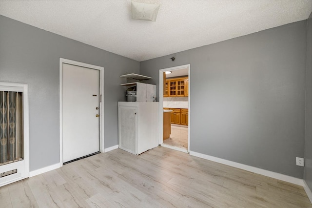 unfurnished room with a textured ceiling and light hardwood / wood-style flooring