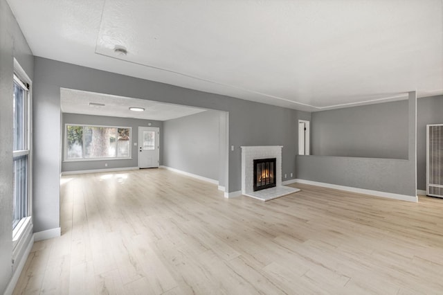 unfurnished living room with a brick fireplace, light hardwood / wood-style flooring, and a textured ceiling