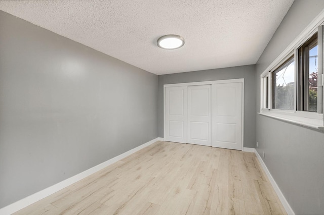 unfurnished bedroom featuring light hardwood / wood-style flooring, a textured ceiling, and a closet