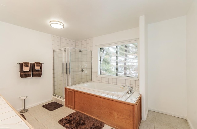 full bath with a stall shower, baseboards, a bath, and tile patterned floors