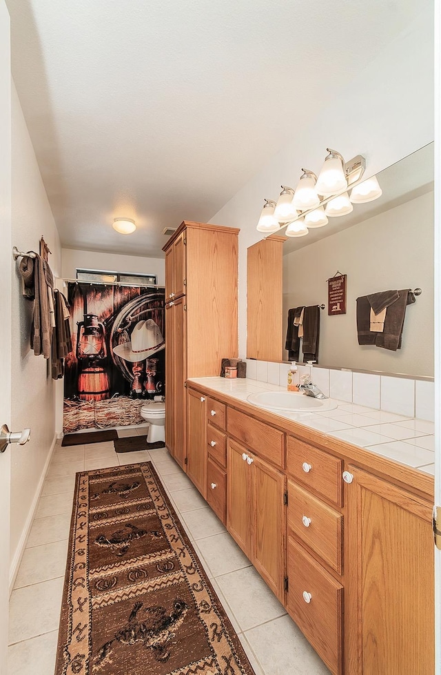 bathroom featuring toilet, vanity, baseboards, and tile patterned floors