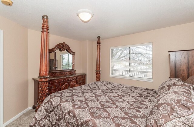 bedroom featuring baseboards, a textured ceiling, and light colored carpet