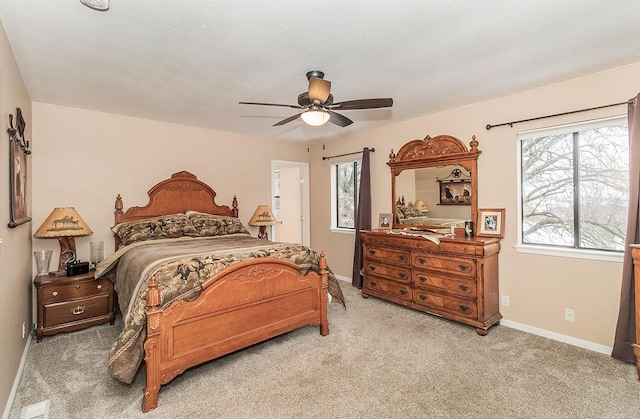 bedroom featuring multiple windows, light carpet, baseboards, and a textured ceiling