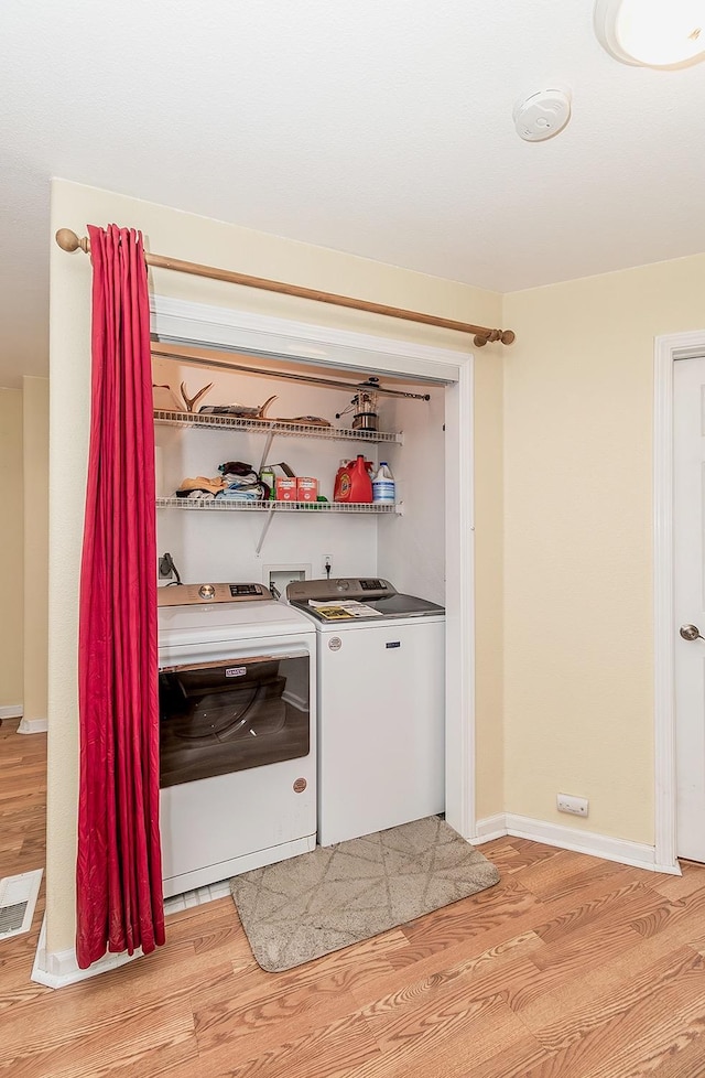 bar featuring visible vents, separate washer and dryer, light wood-style flooring, and baseboards