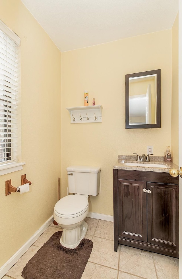 bathroom with toilet, vanity, baseboards, and tile patterned floors