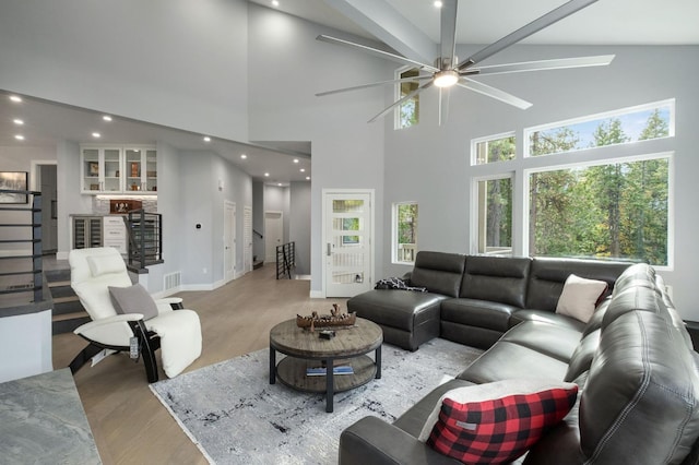 living room with bar, light wood-type flooring, and high vaulted ceiling