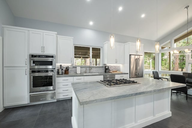 kitchen featuring white cabinets, sink, light stone countertops, appliances with stainless steel finishes, and decorative light fixtures