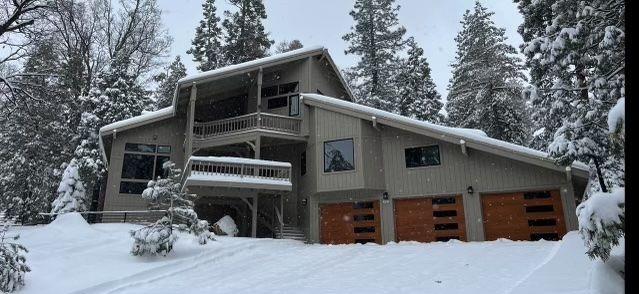 snow covered back of property featuring a balcony