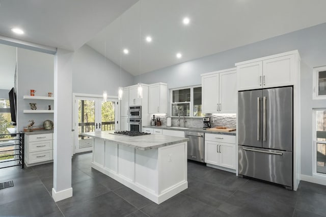 kitchen with pendant lighting, a center island, appliances with stainless steel finishes, light stone counters, and white cabinetry