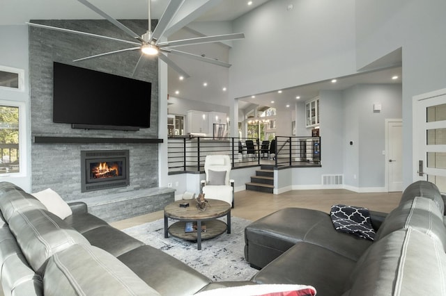 living room with hardwood / wood-style flooring, ceiling fan, a fireplace, and high vaulted ceiling