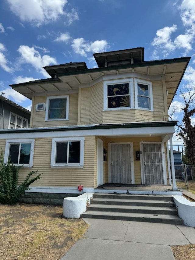 view of front of home with a porch and a wall mounted AC