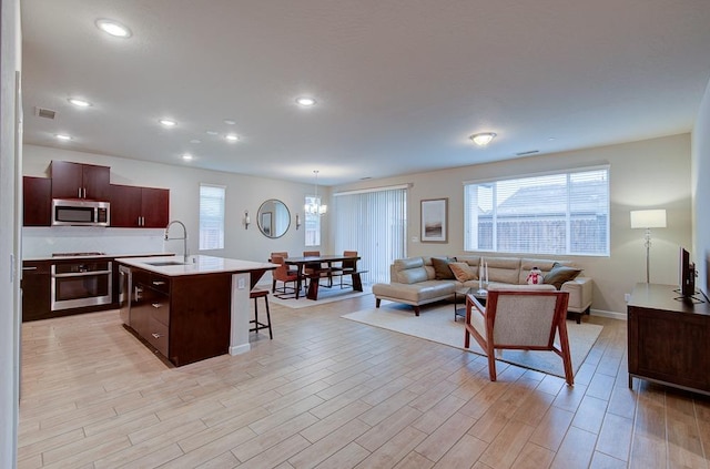 living room with sink, a notable chandelier, and light wood-type flooring