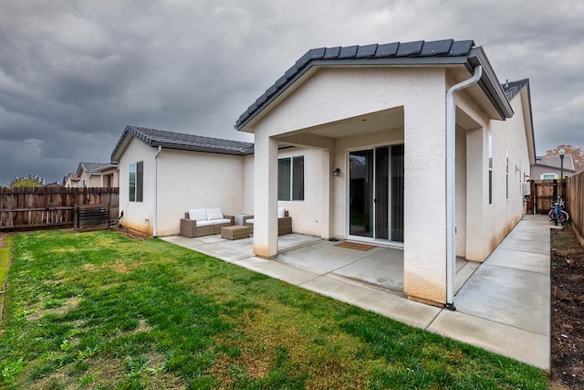 rear view of property with a yard, an outdoor living space, and a patio area