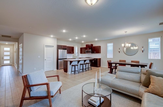 living room with light wood-type flooring, sink, and an inviting chandelier