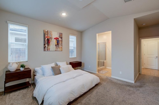 bedroom featuring ensuite bath, light carpet, and vaulted ceiling