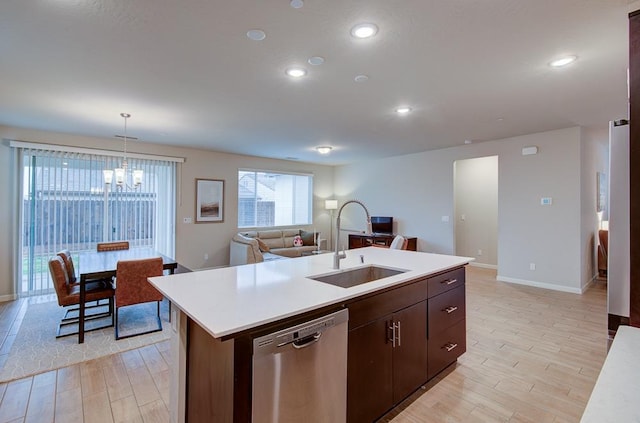 kitchen with pendant lighting, dishwasher, a center island with sink, sink, and light hardwood / wood-style floors