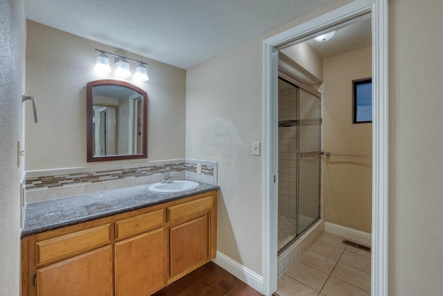 bathroom featuring tile patterned floors, vanity, a shower with door, and a textured ceiling