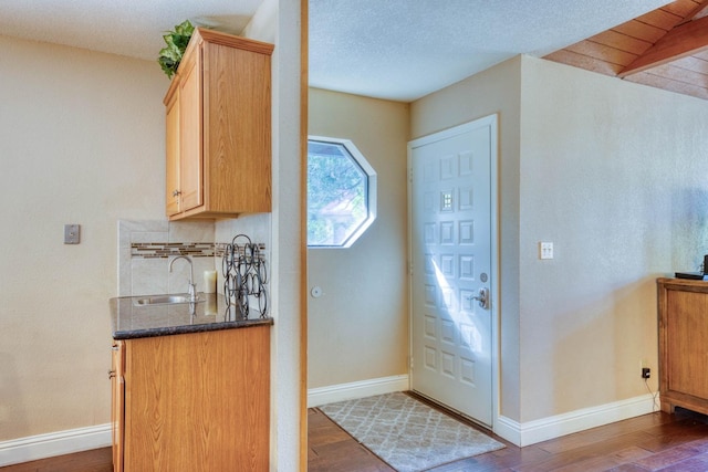 interior space with a textured ceiling, sink, light brown cabinetry, and dark wood-type flooring