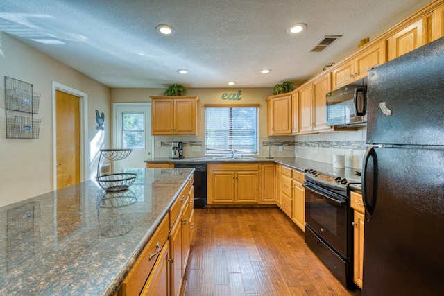 kitchen with black appliances, sink, decorative backsplash, dark stone countertops, and light hardwood / wood-style floors