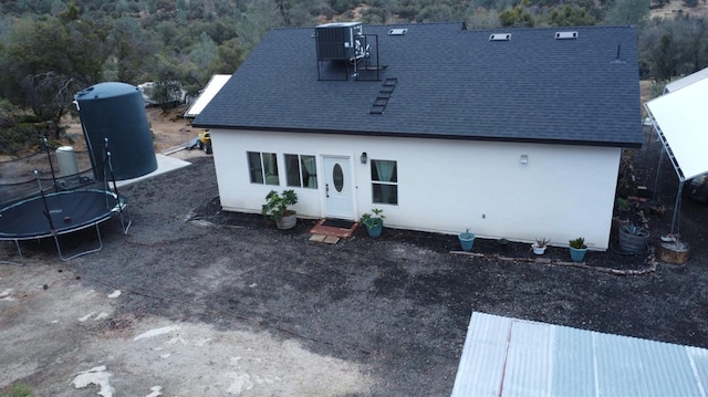 rear view of house with central AC unit and a trampoline