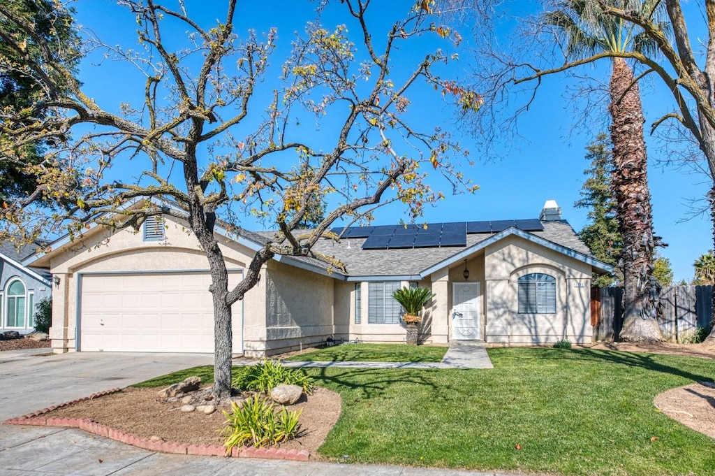 ranch-style house with a garage, a front lawn, and solar panels