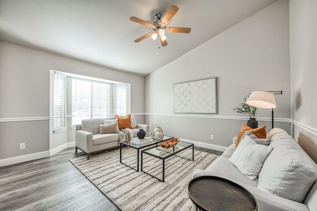 living room featuring hardwood / wood-style flooring, ceiling fan, and vaulted ceiling