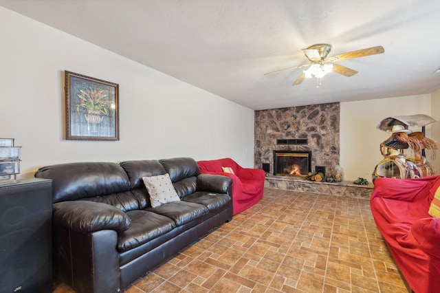 living room featuring ceiling fan and a stone fireplace