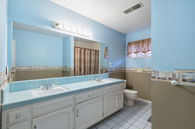 bathroom with toilet, vanity, tile patterned flooring, and a textured ceiling