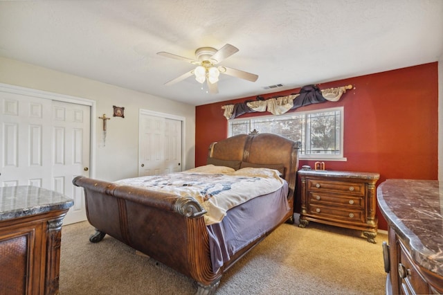 bedroom featuring ceiling fan, two closets, and carpet flooring