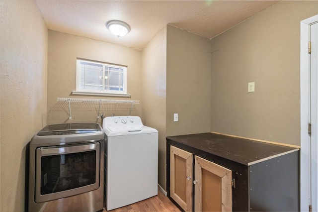 laundry area featuring light hardwood / wood-style floors, separate washer and dryer, and cabinets