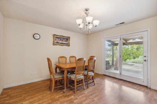 dining room with wood-type flooring and an inviting chandelier