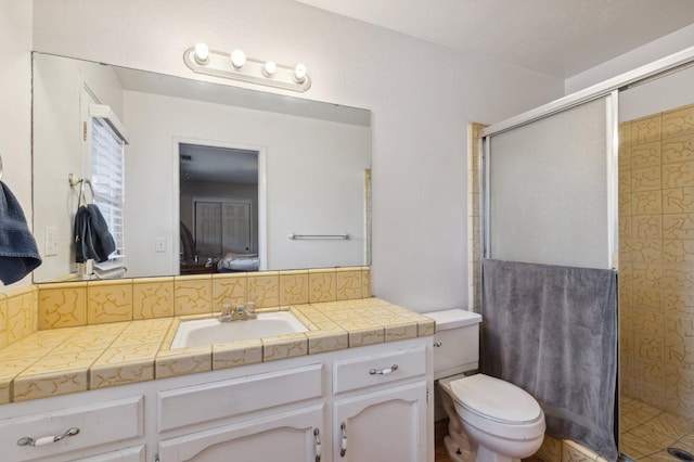 bathroom with toilet, a shower with door, vanity, and tasteful backsplash