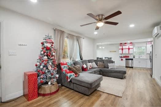 living room with a wall mounted AC, hardwood / wood-style floors, and ceiling fan