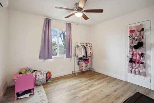 interior space with hardwood / wood-style flooring, a wall mounted air conditioner, and ceiling fan