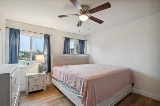 bedroom with ceiling fan, multiple windows, and light wood-type flooring