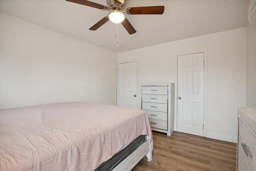 bedroom featuring ceiling fan, hardwood / wood-style floors, and two closets