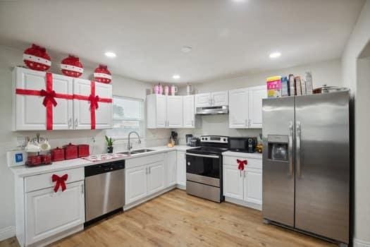 kitchen featuring stainless steel appliances, white cabinetry, sink, and light hardwood / wood-style flooring