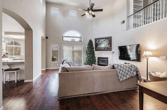 living room featuring ceiling fan, dark wood-type flooring, and a high ceiling