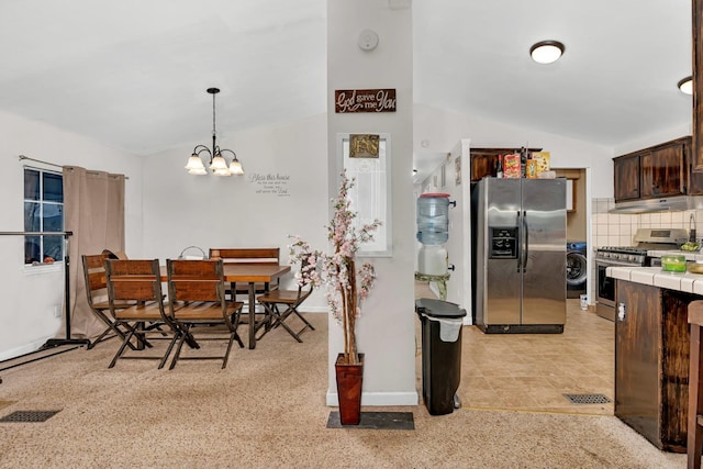 kitchen with dark brown cabinetry, hanging light fixtures, vaulted ceiling, decorative backsplash, and appliances with stainless steel finishes