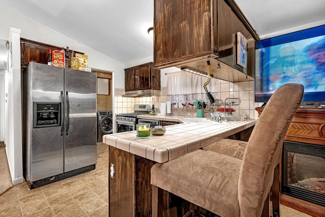 kitchen featuring backsplash, dark brown cabinets, stainless steel appliances, vaulted ceiling, and tile countertops