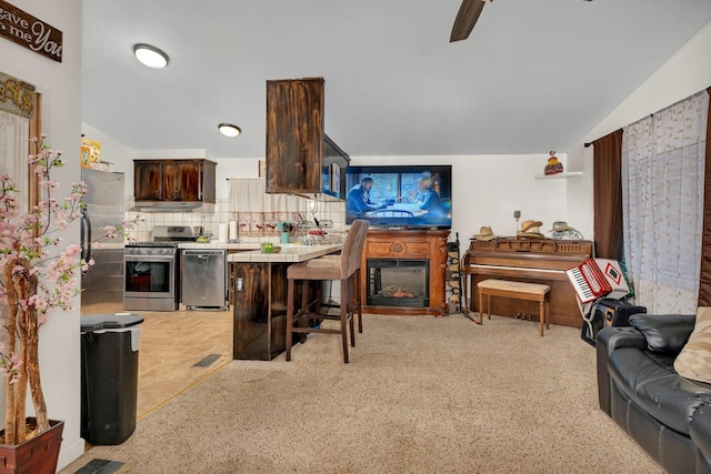 kitchen with a breakfast bar, lofted ceiling, appliances with stainless steel finishes, tasteful backsplash, and dark brown cabinets