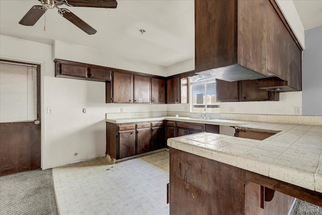 kitchen with kitchen peninsula, tile counters, dark brown cabinets, and ceiling fan