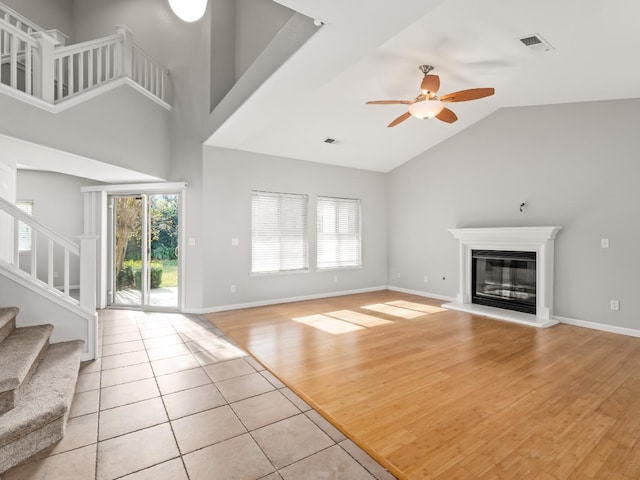 unfurnished living room with high vaulted ceiling, ceiling fan, and light tile patterned flooring