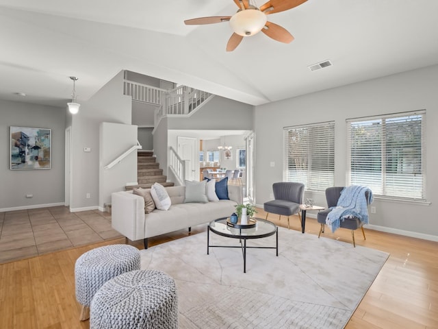 living room with ceiling fan with notable chandelier, lofted ceiling, and light hardwood / wood-style floors